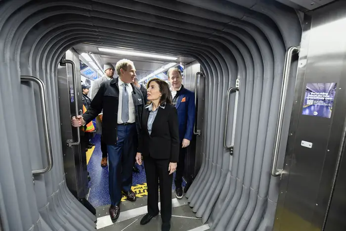 MTA Chair Janno Lieber and Gov. Kathy Hochul stand in an "accordion" section linking two train cars.